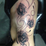 Zwarte rozen tatoeage op de zij van ene vrouw