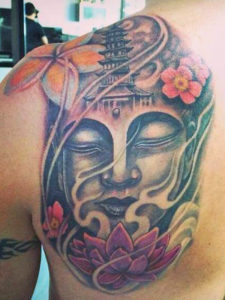 Tattoo van een groot budha hoofd geplaatst op de rug met veel kleurgebruik vooral in de bloemen