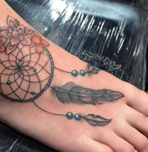 Mooie dromenvanger tatoeage met veren eraan op de voet van een vrouw