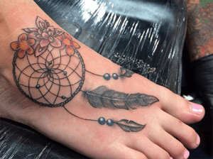 Mooie dromenvanger tatoeage met veren eraan op de voet van een vrouw