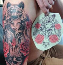 tattoo van een meisje met een tijgervel omringt met rozen, geplaatst op bovenarm
