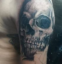 Realistische skull tatoeage geplaatst op de bovenarm door tattooshop Dutchink