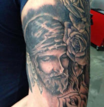 tatoeage van Jezus met dornen kroon en rozen geplaatst op de bovenarm