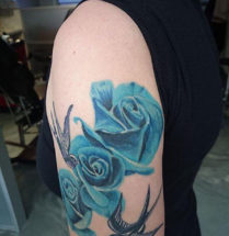 tattoo van drie realistische blauwe rozen en twee old school zwaluwen erbij