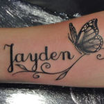 Naam tatoeage met een vlinder rbij op de onderarm