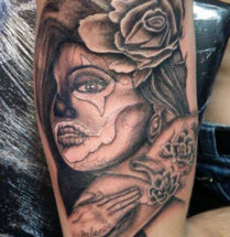 chicano tattoo van een vrouw met enkele kleine rozen geplaatst op de bovenarm bij Dutch Ink