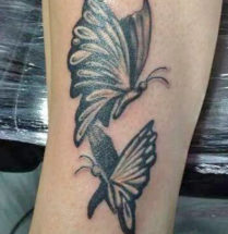 tatoeage op de pols van twee zwarte vlinders waar gebruik is gemaakt van dikke lijnen.