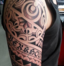 tribal tatoeage geplaatst op de bovenarm met een tekst erin