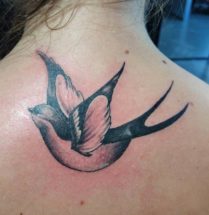 Zwart witte zwaluw tattoo in de nek