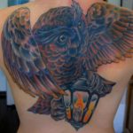 Creatieve uilen tattoo met veel kleur geplaatst over de gehele rug