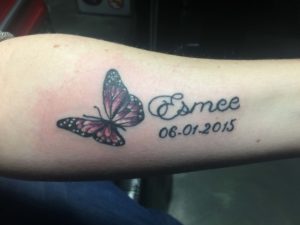 Vlinder en namen tattoo op onderarm